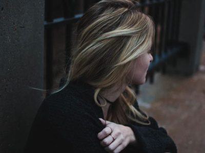 Girl looking away from camera with blonde hair in a dark street during the day