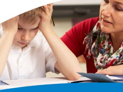 School child at desk with head in hands, female teacher looking concerned for him