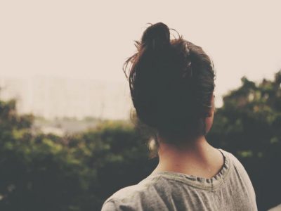 Young woman facing the trees with her back to you