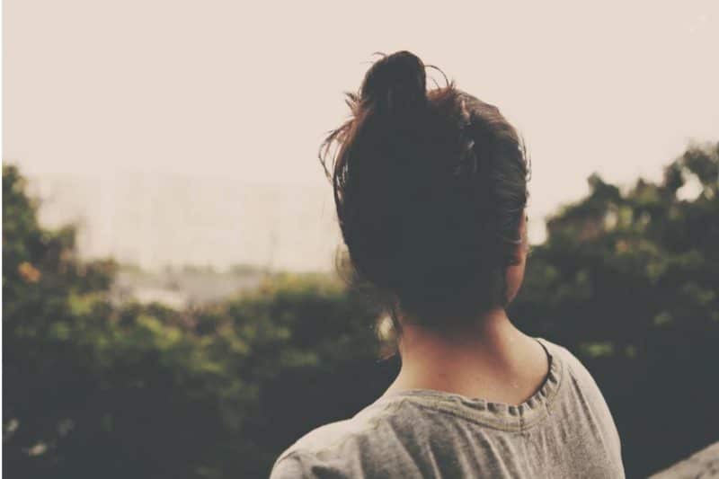 Young woman facing the trees with her back to you