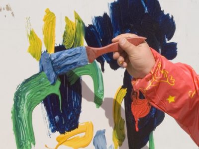 Child's hand painting on a wall with coloured paints