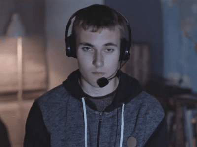 A teenage boy playing an online video game while wearing a headset