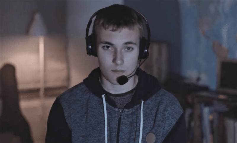 A teenage boy playing an online video game while wearing a headset