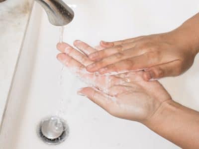 Someone washing their hands under a tap with soap and water