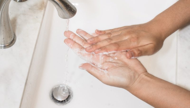 Someone washing their hands under a tap with soap and water