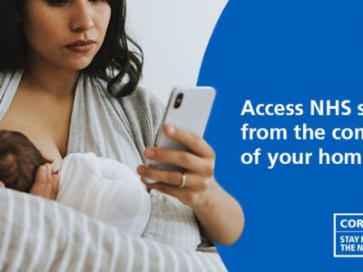 An NHS Health at Home poster. A woman holding a baby while checking her mobile phone.