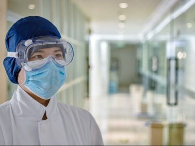 A doctor wearing a surgical mask, goggles and protective headgear