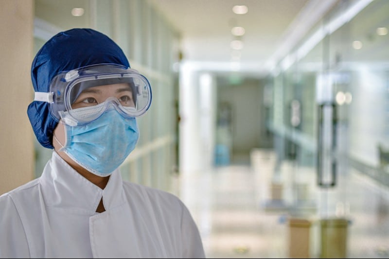 A doctor wearing a surgical mask, goggles and protective headgear