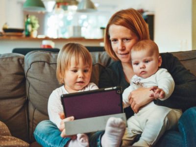 a mother and two children looking at an iPad