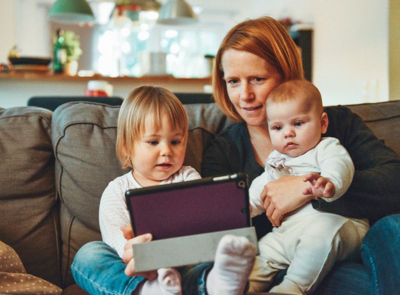 a mother and two children looking at an iPad