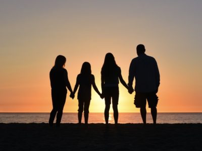 a family of four silhouetted against a sunset