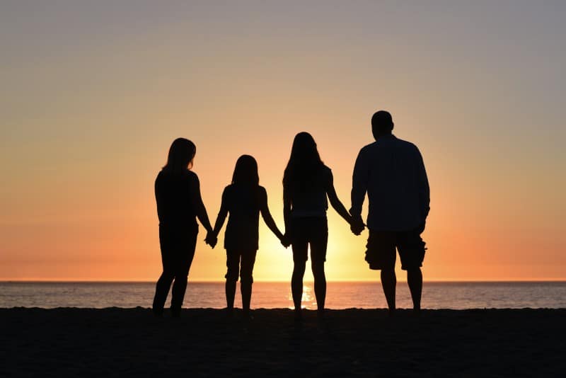 a family of four silhouetted against a sunset