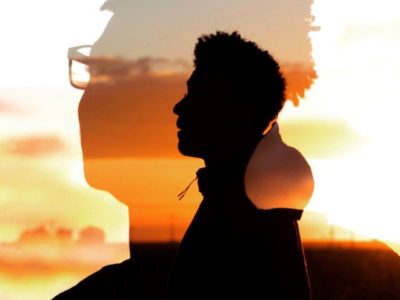 a silhouette of a man's head against a sunset