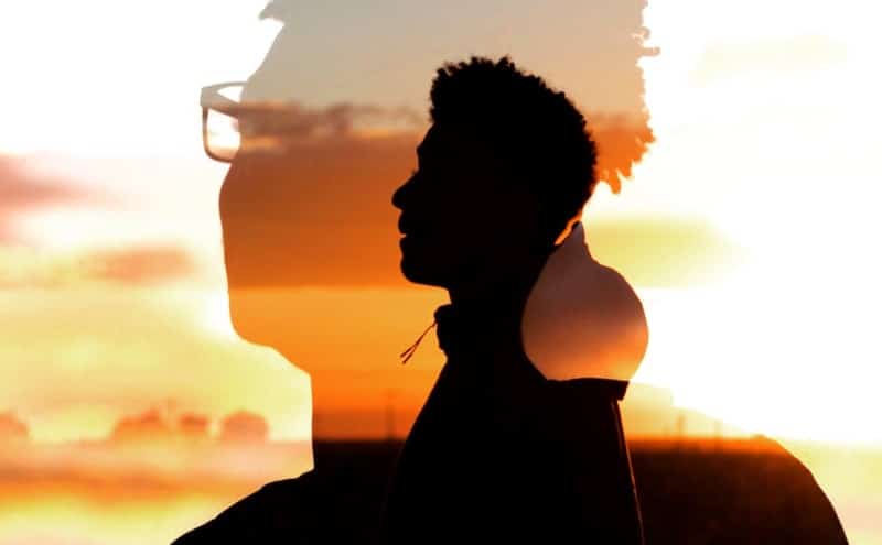 a silhouette of a man's head against a sunset