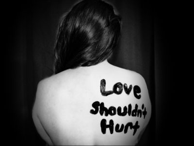 a woman with "love shouldn't hurt" written on here back