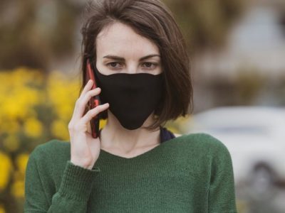 a woman wearing a face mask using a mobile phone