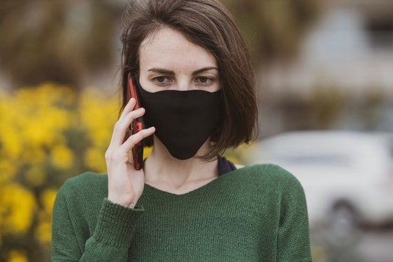 a woman wearing a face mask using a mobile phone