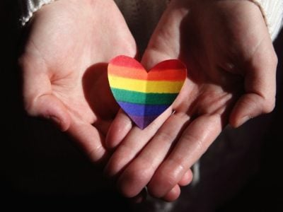 a person holding a rainbow-coloured heart