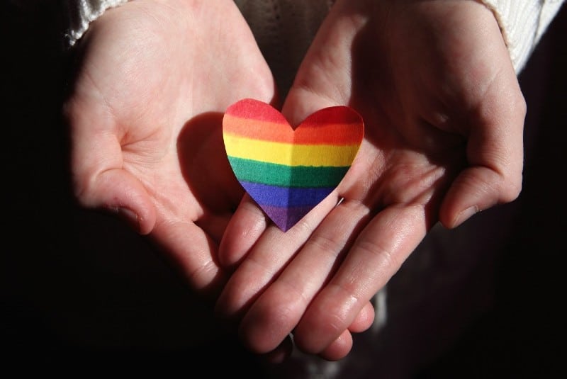 a person holding a rainbow-coloured heart