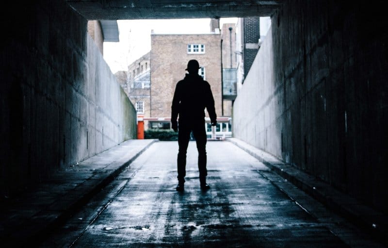 a shadowy figure standing in an underpass