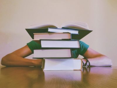 a person hidden behind a stack of books