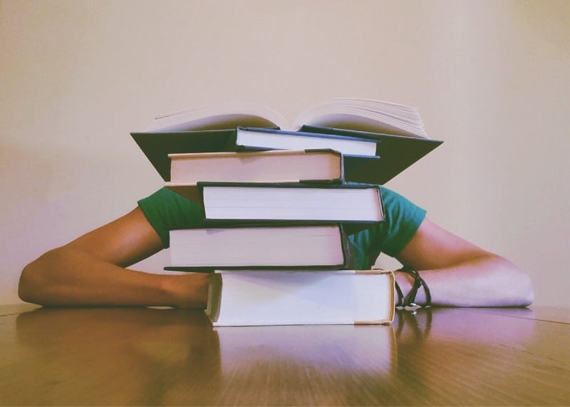 a person hidden behind a stack of books