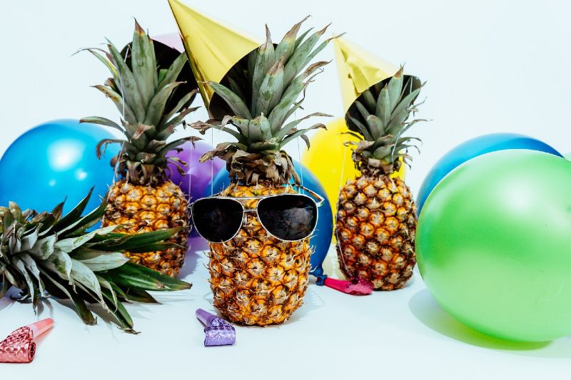 three pineapples surrounded by balloons