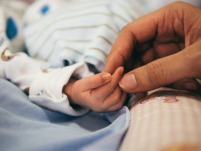 A tiny baby grabbing a adult's hand