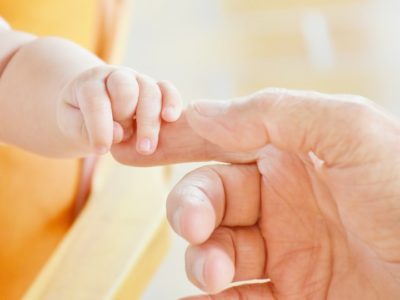 A tiny baby grabbing an adult's hand