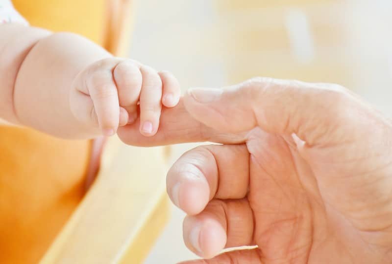 A tiny baby grabbing an adult's hand