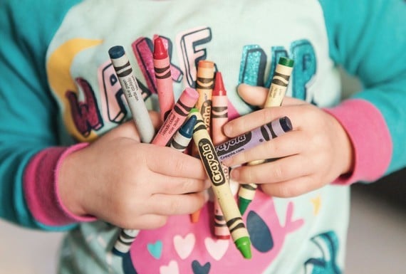 a child carrying crayons