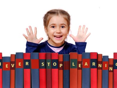 a happy girl behind some books that say never stop learning