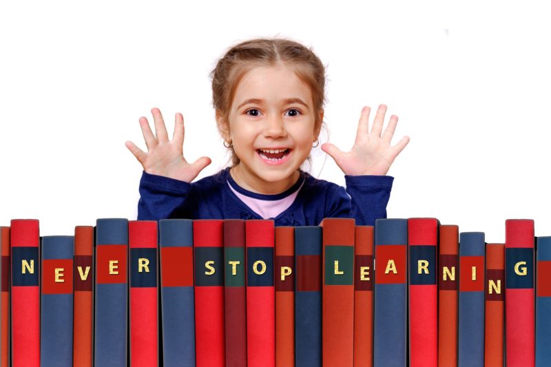 a happy girl behind some books that say never stop learning