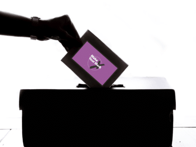 a hand placing a vote into a ballot box