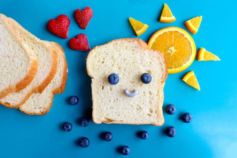 a slice of bread with a smiley face made out of blueberries