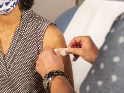 a doctor putting a plaster on a patient's arm after a vaccine