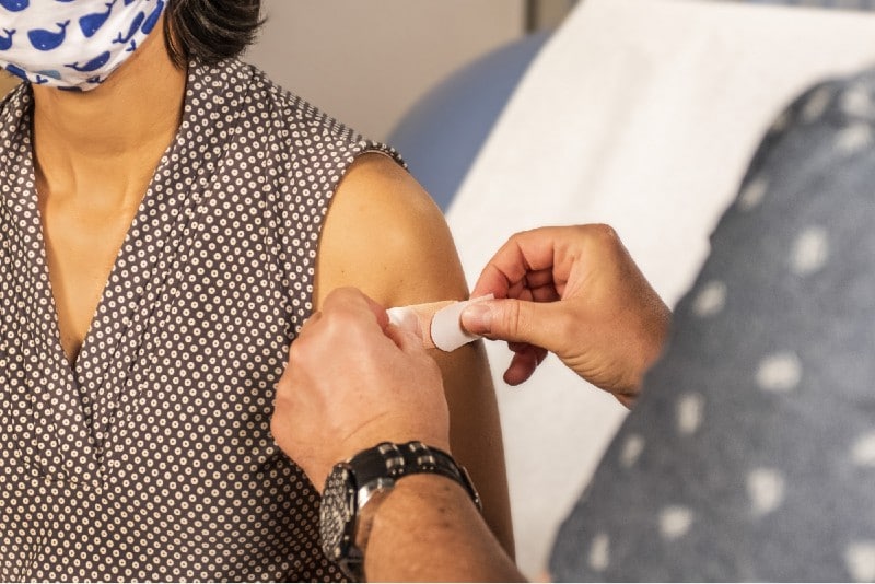 a doctor putting a plaster on a patient's arm after a vaccine