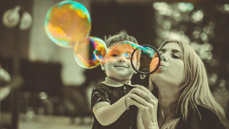 a mother and child blowing bubbles