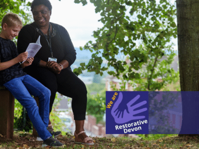 a child and a care worker sat on a bench