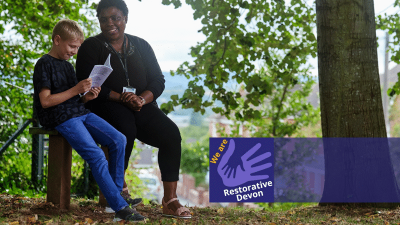 a child and a care worker sat on a bench